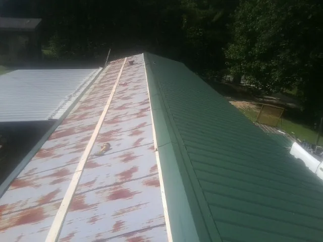 Old rusted panels beside newly installed green metal roofing — Wind Damage Roof Repair by Roofing Brothers in Hickory Corners
