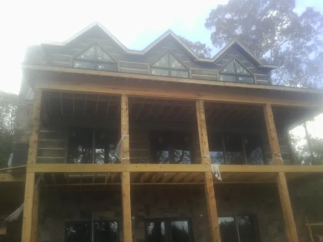 Dormers and porch framing on a large log home under construction — Roof Coating work by our crew in Hickory Corners