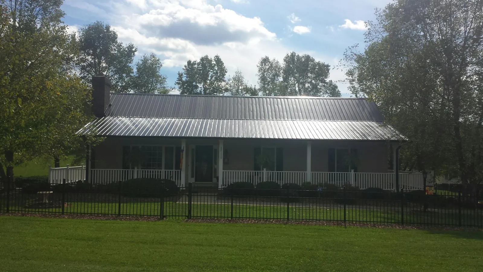 Gray metal roof on a brick ranch with a full width front porch — Gutter Guard Installation work by our crew in Hickory Corners