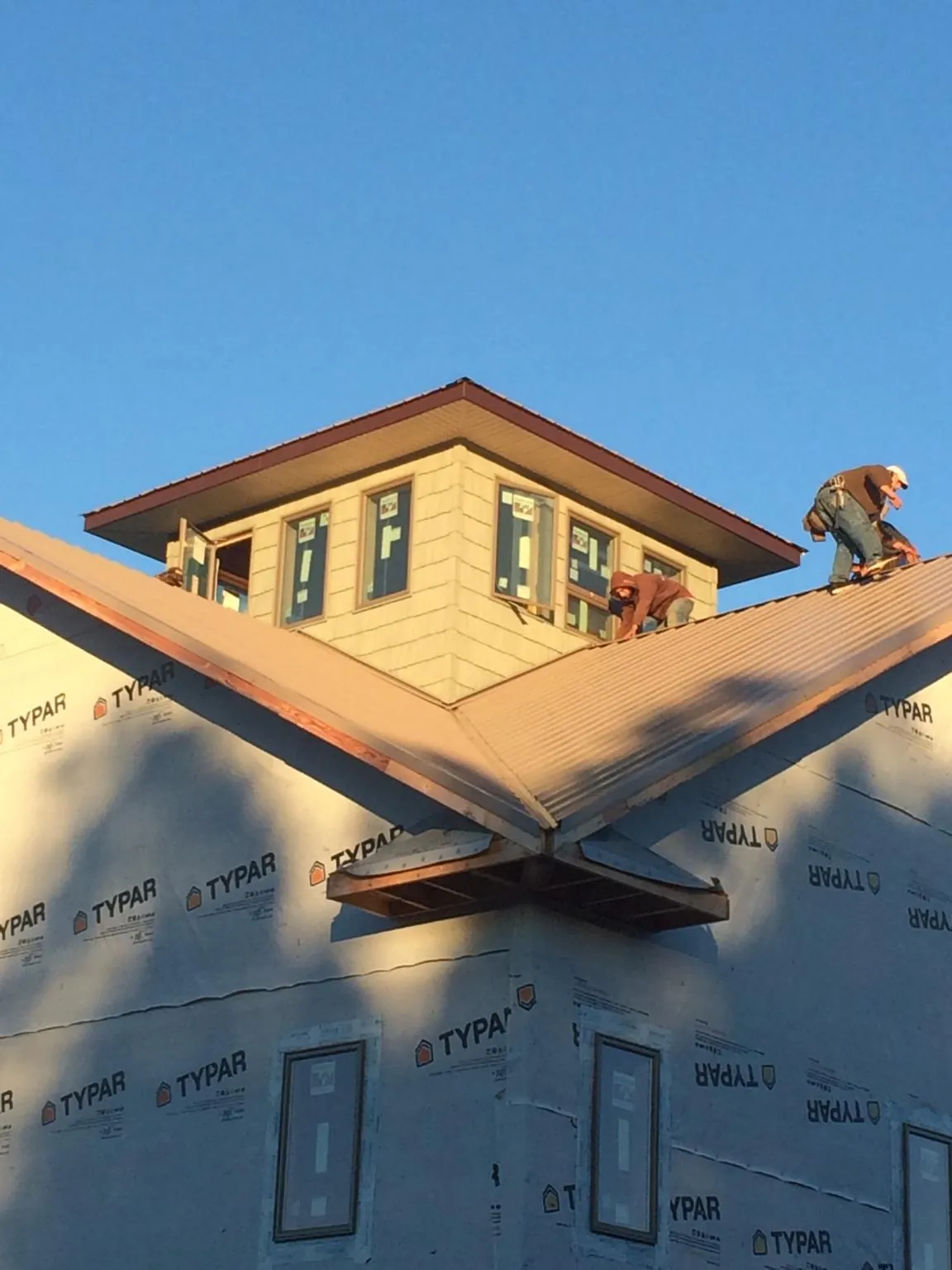 Roofers working around a rooftop cupola on a new metal roof at sunset — Roof Waterproofing in Hickory Corners by Roofing Brothers
